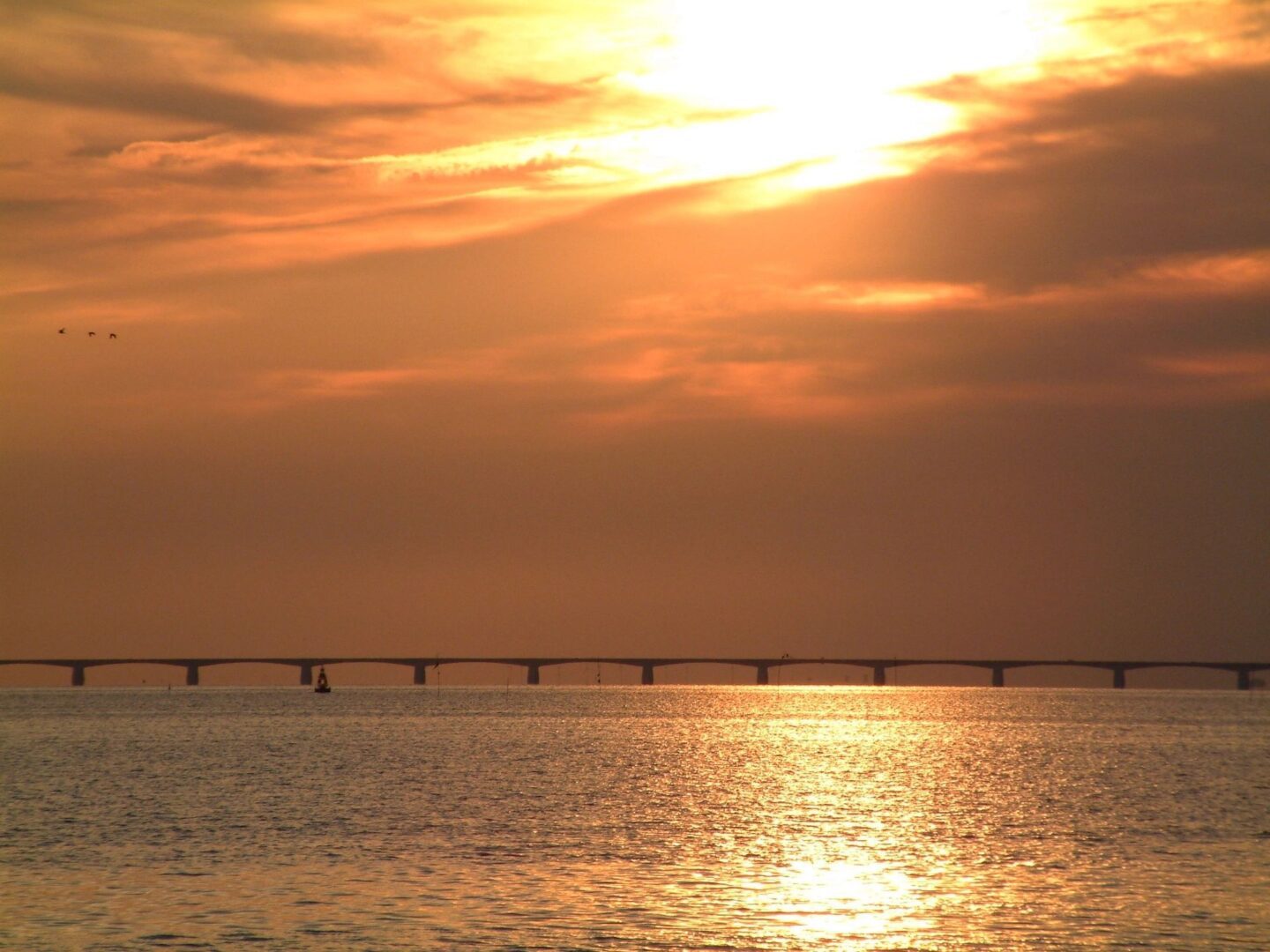 A sunset over the ocean with an orange sky.