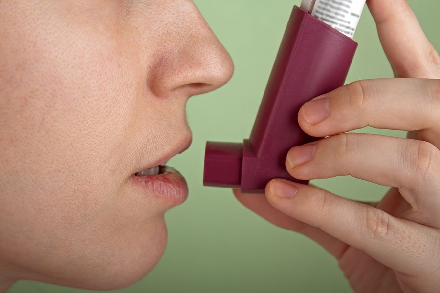 A person holding an inhaler in their mouth.