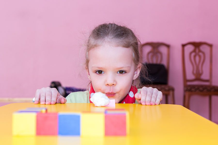 A little girl sitting at the table with blocks